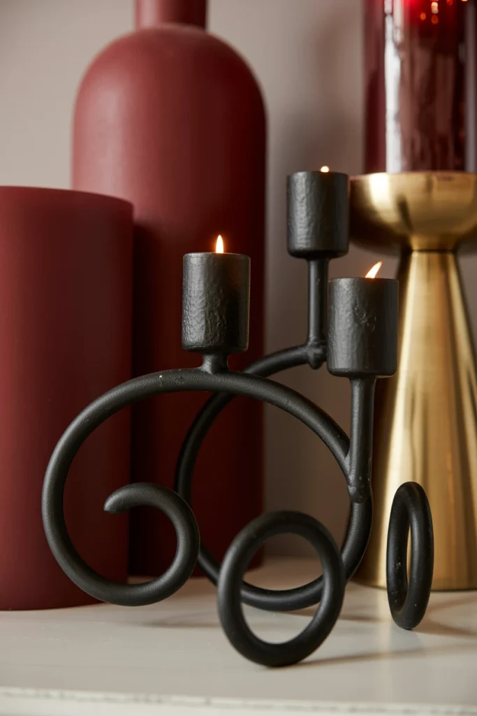 Black iron candle holders grounding a burgundy and gold vignette