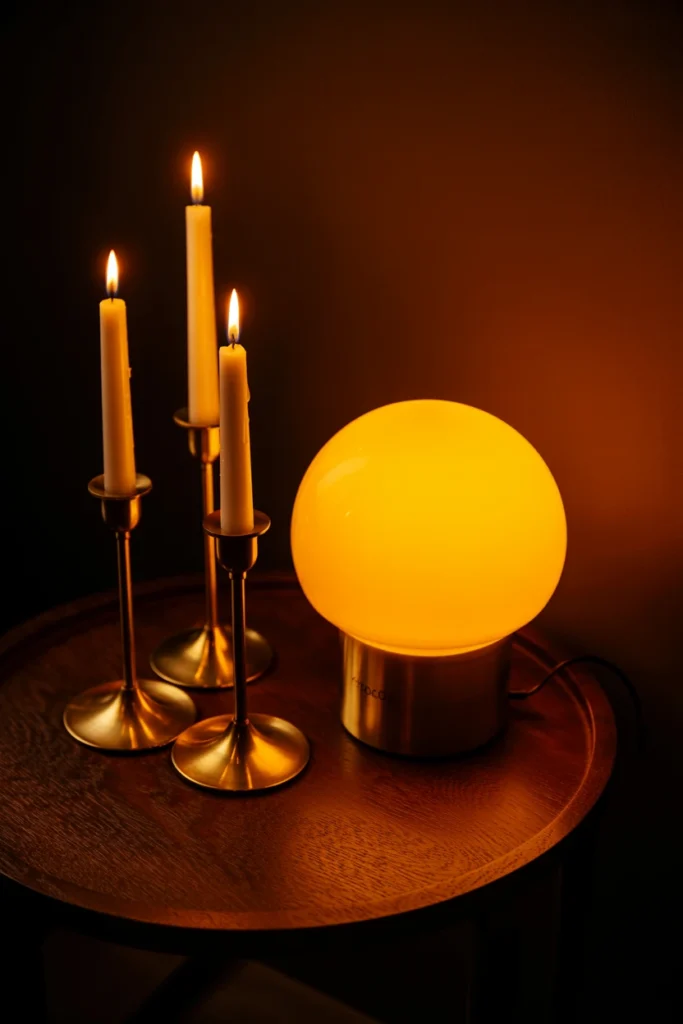 Warm amber lamp glow beside brass candlesticks