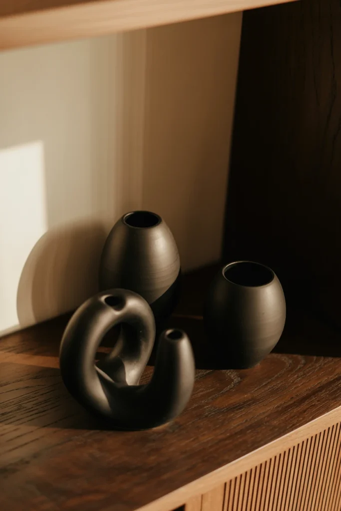 Three black ceramic objects grouped on a shelf at varying heights