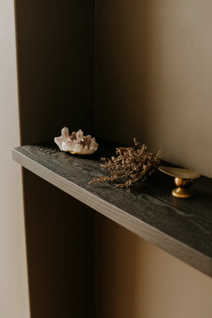 Dark wood floating shelf displaying crystals and dried botanicals