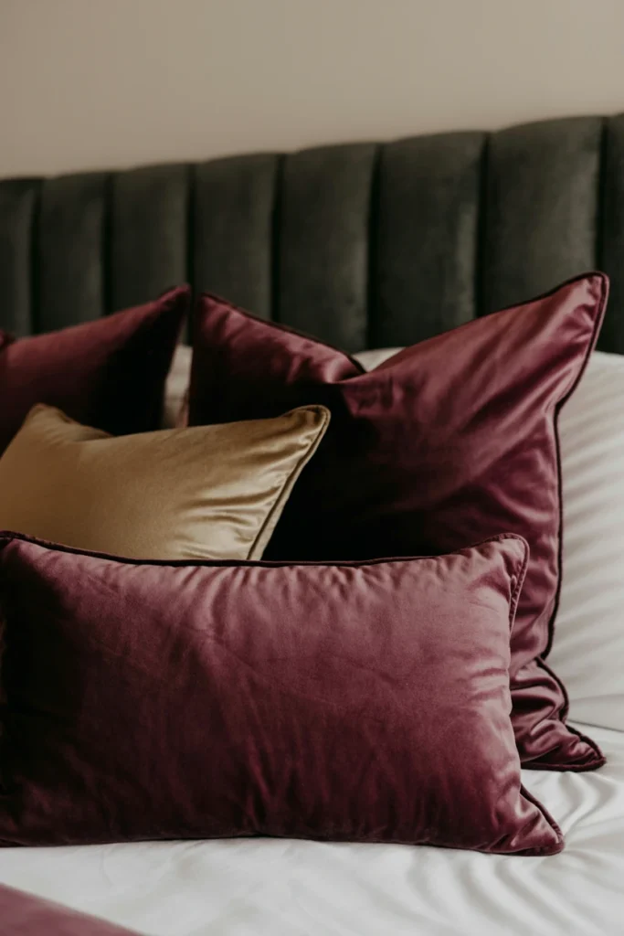 Two plum velvet pillows against a charcoal headboard