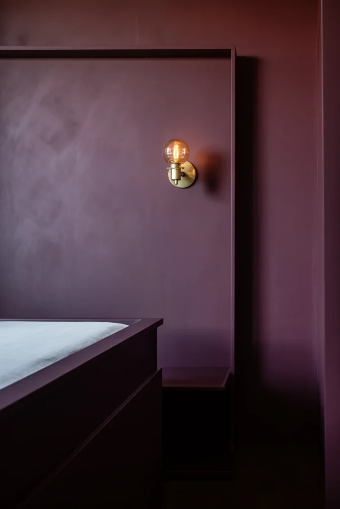 Deep plum accent wall with brass wall sconce
