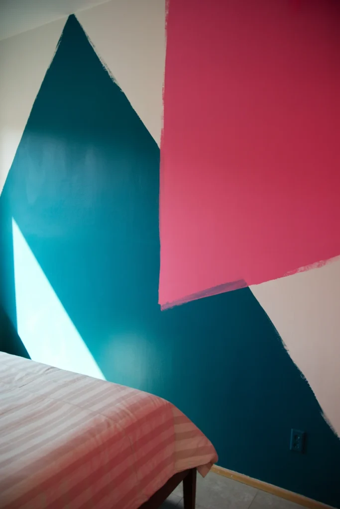 Color-blocked bedroom wall with triangle and rectangle shapes in teal and pink