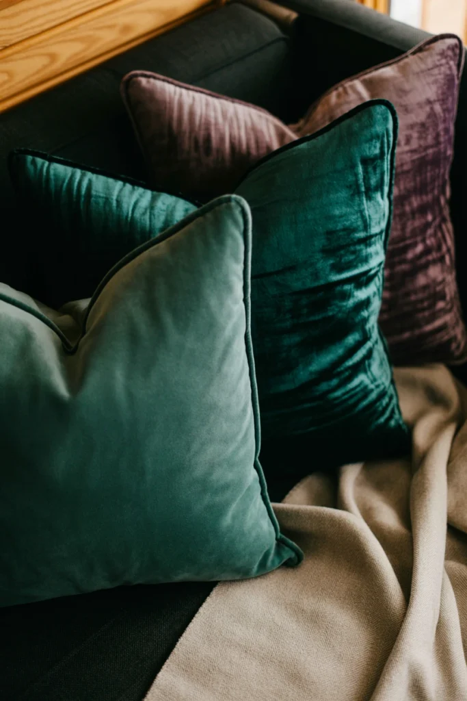 Emerald velvet throw pillows layered on a dark sofa