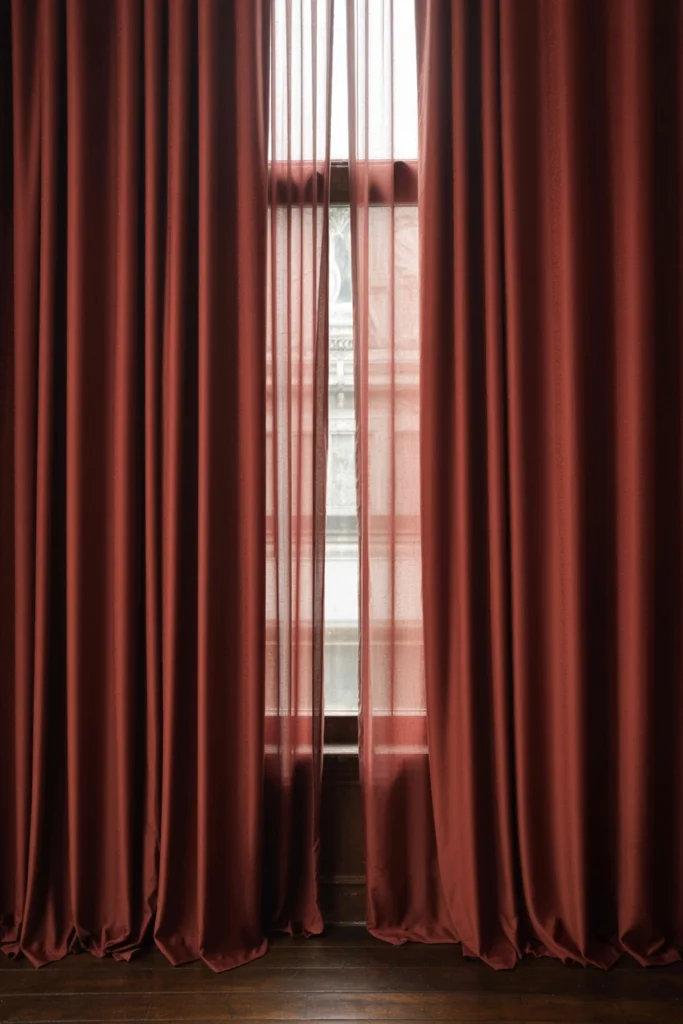 Floor-to-ceiling burgundy velvet curtains framing a large window