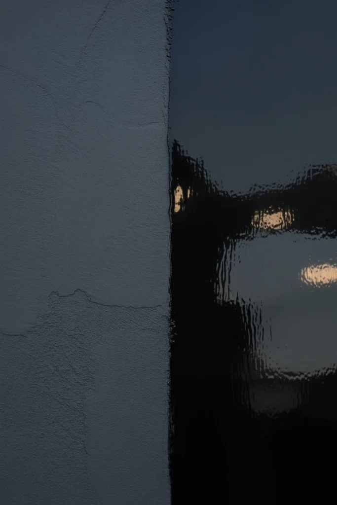 Close-up comparison of matte versus glossy black paint on a wall