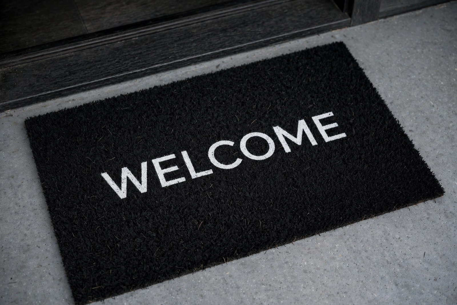 Black coir Halloween welcome mat centered at a porch door